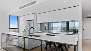 Una cocina moderna con una isla grande, armarios blancos y vistas al exterior.