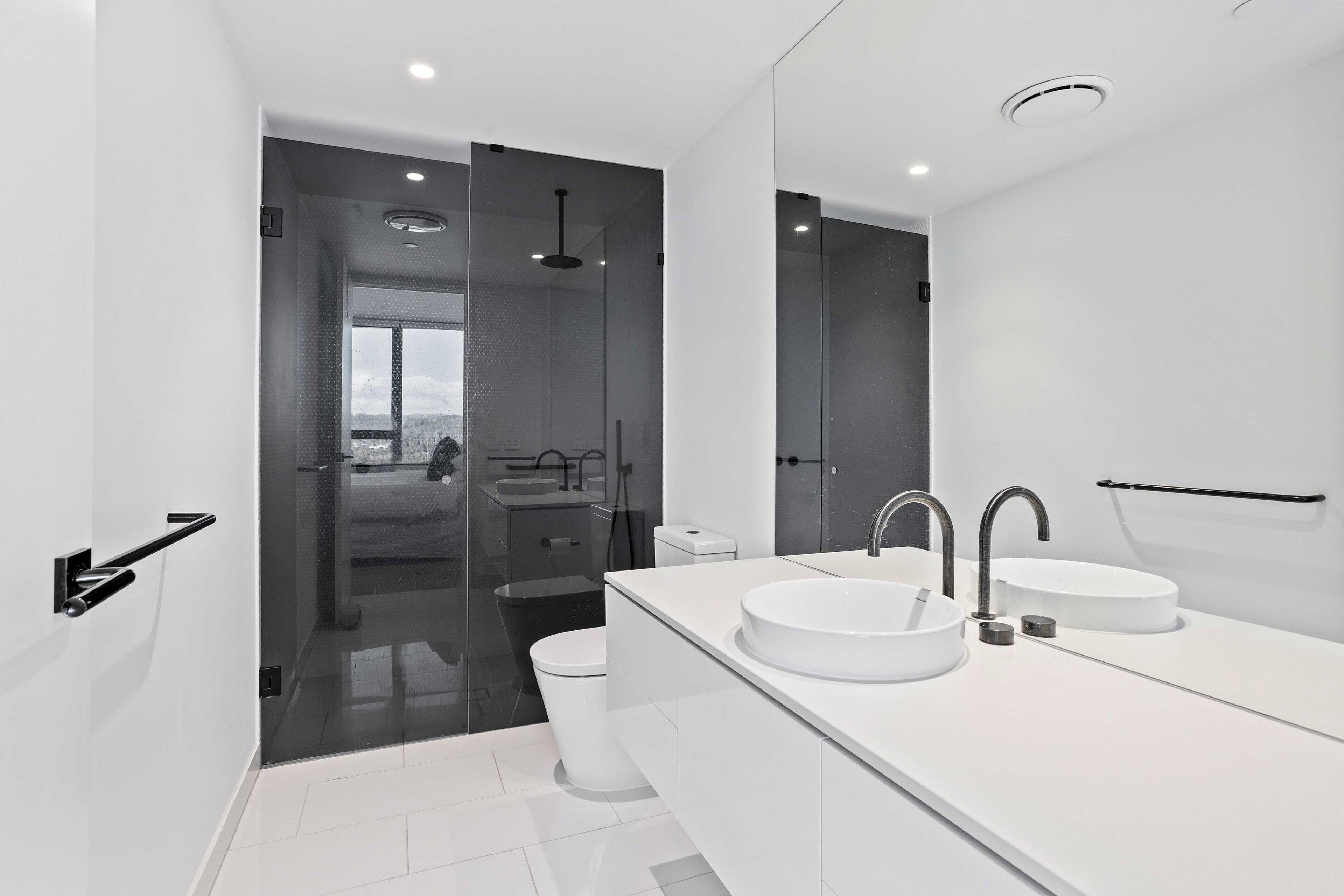 Een moderne badkamer met een grote spiegel, twee wasbakken en een douche.