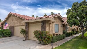 A single-story house with a beige exterior, a red-tiled roof, and a garage door.