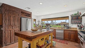 A kitchen with a wooden island, stainless steel appliances, and a view of the outdoors.