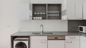 A compact kitchen with a built-in dishwasher, a microwave, and a sink. - Outstanding Neubau 3BR w/ Elevator & Laundry, by Blueground (Vienna)