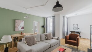 A modern living room with a sofa, a coffee table, a dining table, and a chair. - Outstanding Neubau 3BR w/ Elevator & Laundry, by Blueground (Vienna)