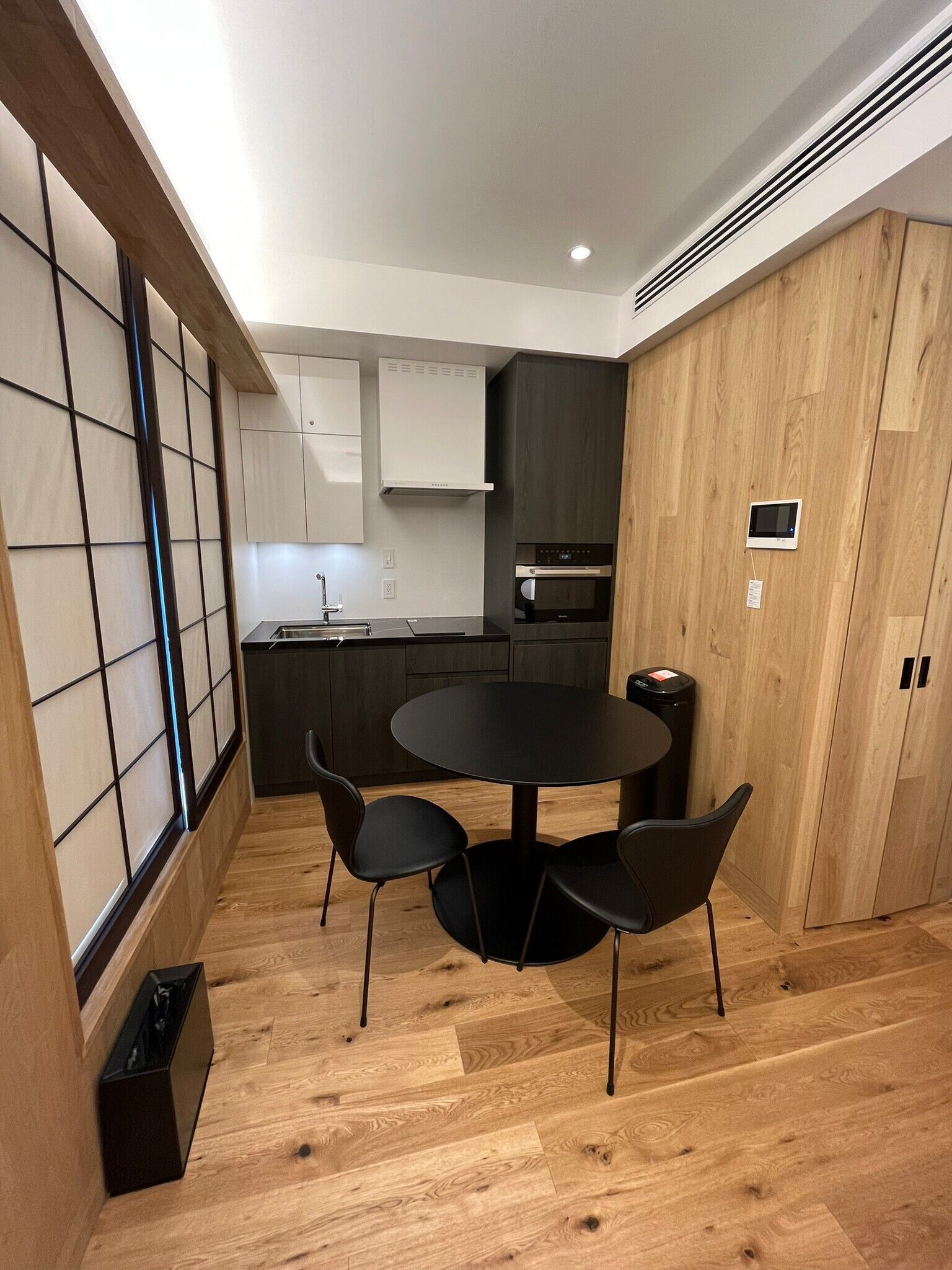 A modern kitchen with a round dining table and four chairs, wooden flooring, and built-in cabinets.