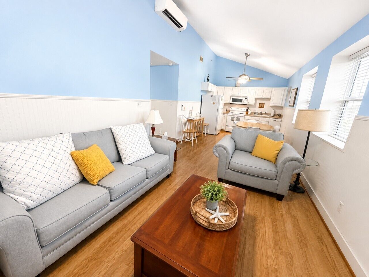 A living room with two sofas, a coffee table, and a kitchen in the background.
