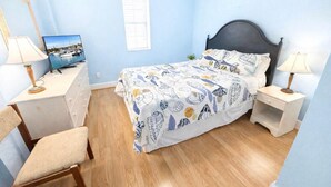 Ein Schlafzimmer mit einem Bett, einem Schreibtisch, einem Stuhl und einem Fernseher.