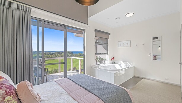 A bedroom with a large bed, a bathroom with a bathtub, and a balcony with a view. - Luxurious 2-Bedroom Spa Apartment with Ocean Views (KRONKUP)