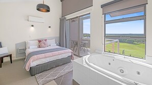 A modern bedroom with a large bed, a bathroom with a bathtub, and a balcony with a view. - Luxurious 2-Bedroom Spa Apartment with Ocean Views (KRONKUP)