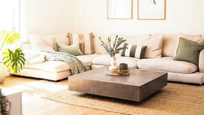 A living room with a beige sectional sofa, a concrete coffee table, and two framed artworks on the wall. - Casa Blanca - Lakeside Luxury (Mount Warrigal)