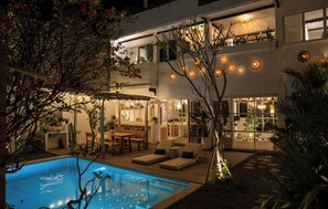 A modern house with a swimming pool, outdoor seating, and a well-lit patio area. - Balai Amaia (Canggu)