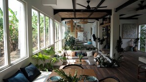 Un amplio salón con ventanas grandes, techo de madera y una variedad de plantas.