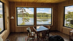 Una cabaña de madera con un ventanal grande que da a un lago y un bosque.