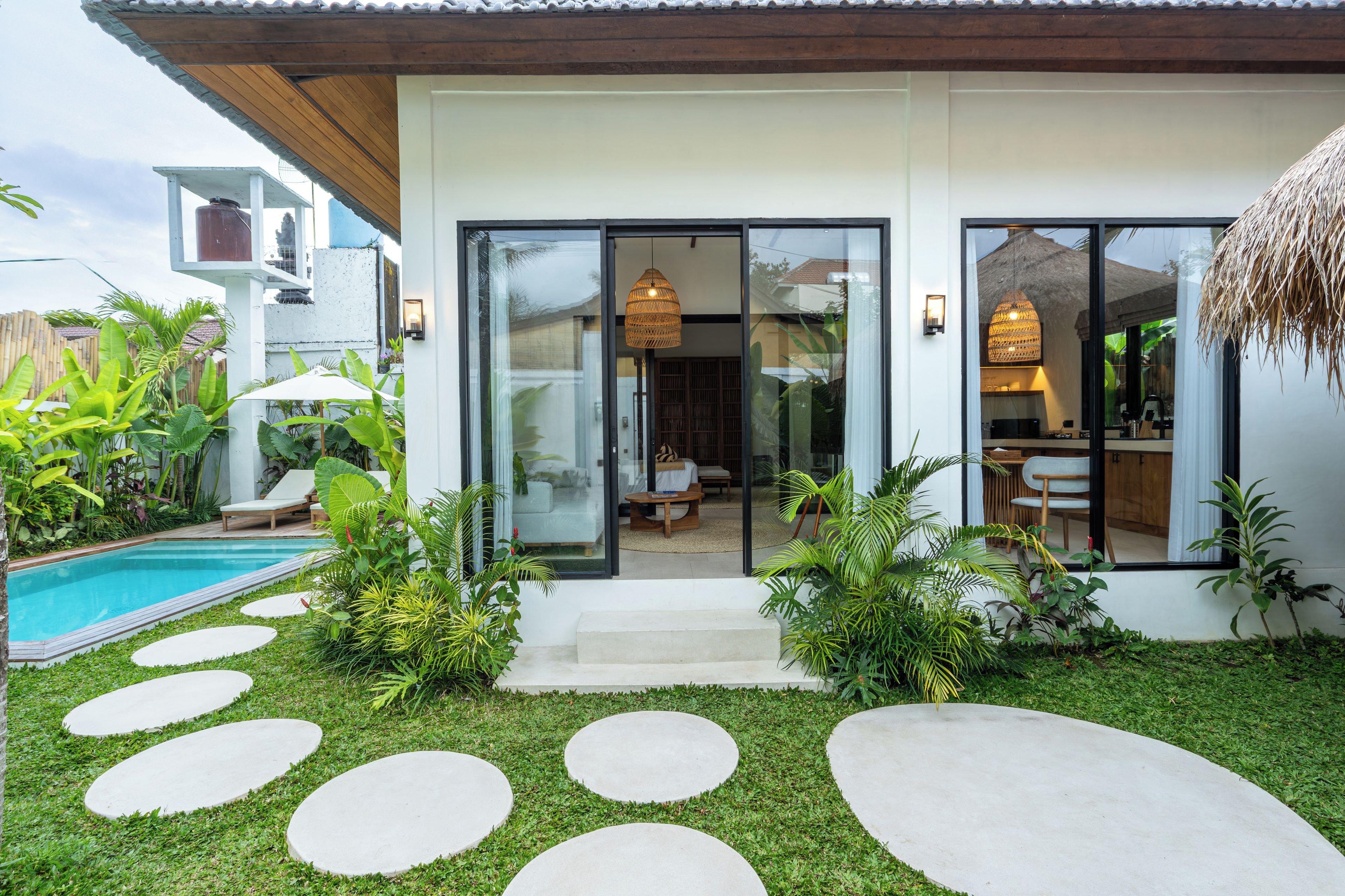 Ein modernes Haus mit Swimmingpool, einer Terrasse mit Treppe zum Eingang und einem gepflegten Garten.