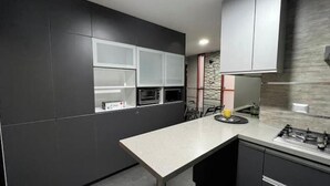 Une cuisine moderne avec des meubles de couleur sombre, un îlot central et une cuisinière à gaz.