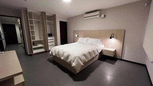 Une chambre à coucher moderne, équipée d’un lit, de tables de chevet, d’une armoire et d’un appareil de climatisation.