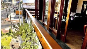 Une pièce avec vue sur le paysage urbain, un balcon agrémenté de plantes et un plancher en bois.