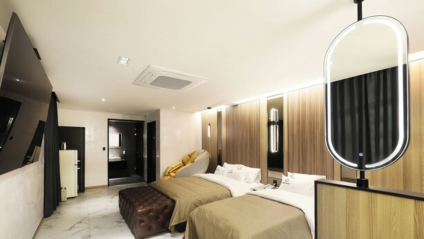 A modern hotel room with a bed, bedside tables, a mirror, and a bathroom visible through an open door. - Cielo Hotel (Jecheon)
