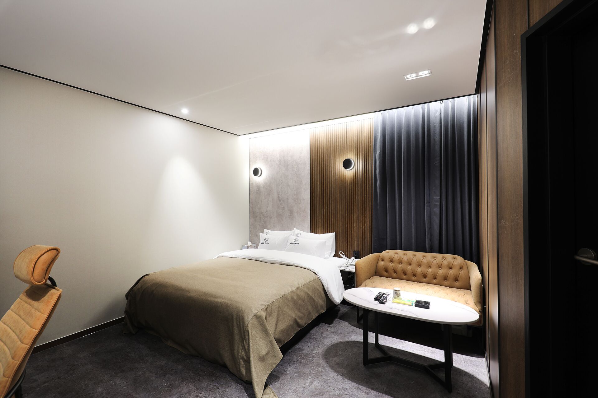 A hotel room with a bed, a sofa, a small table, and a chair.