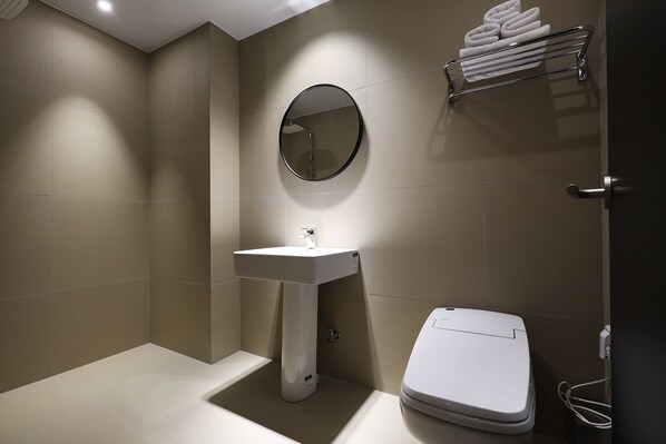 Een moderne badkamer met een wastafel op voet, een toilet en een handdoekhouder.