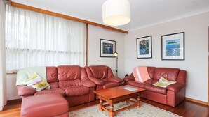A living room with two red leather sofas, a wooden coffee table, and a floor lamp. There are three framed pictures on the wall. - Jimmys Beach Waterfront (Hawks Nest)