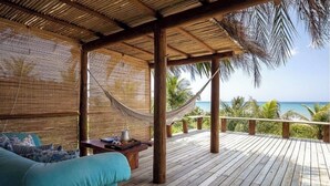 Eine Holzterrasse mit einer Hängematte, einer Sitzecke und einem Tisch mit einer Auflage.