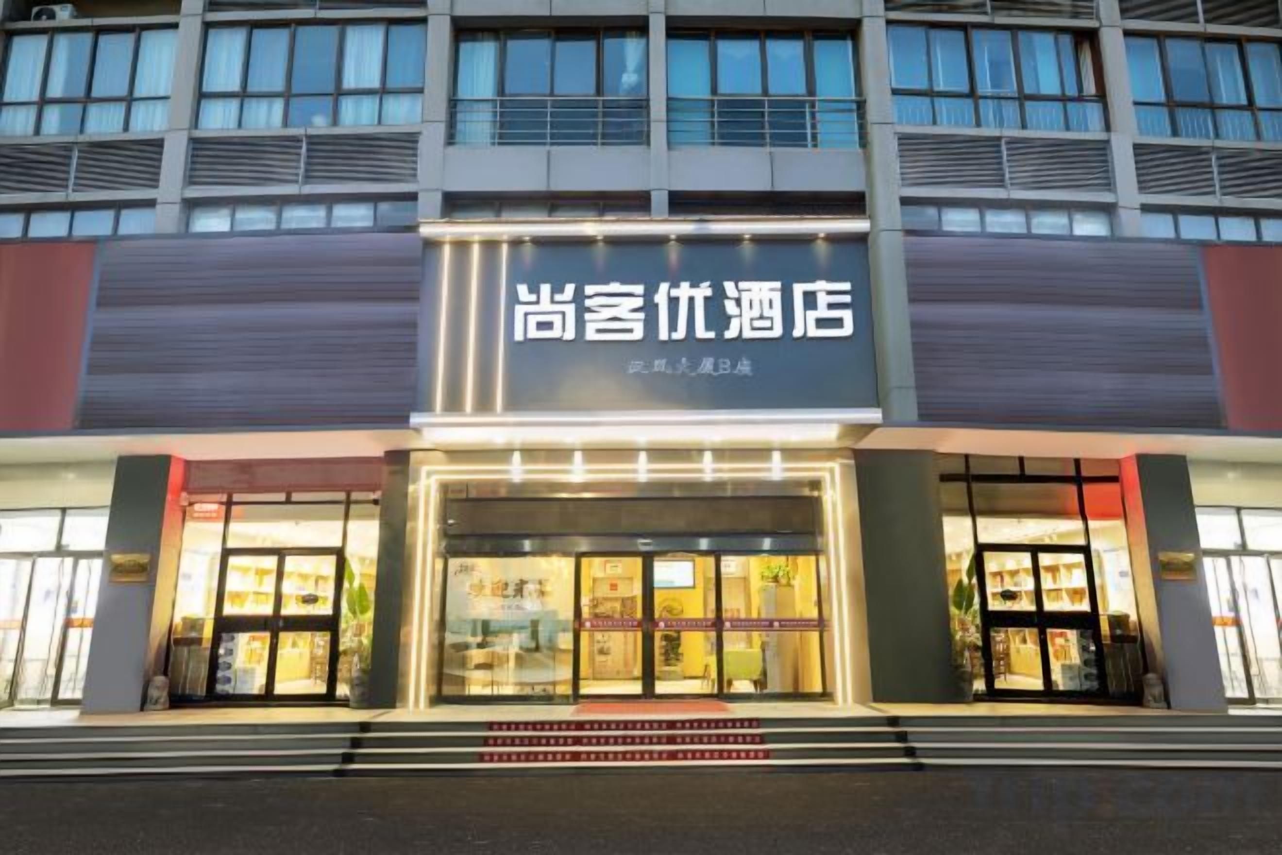 A hotel entrance with a sign in Chinese characters, a glass door, and a staircase leading up to the entrance.