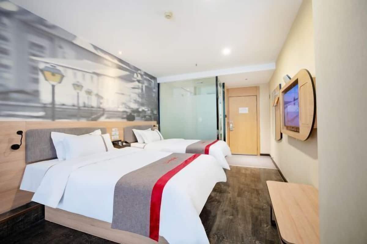 A hotel room with two beds, a large window, a TV, and a wooden bench.