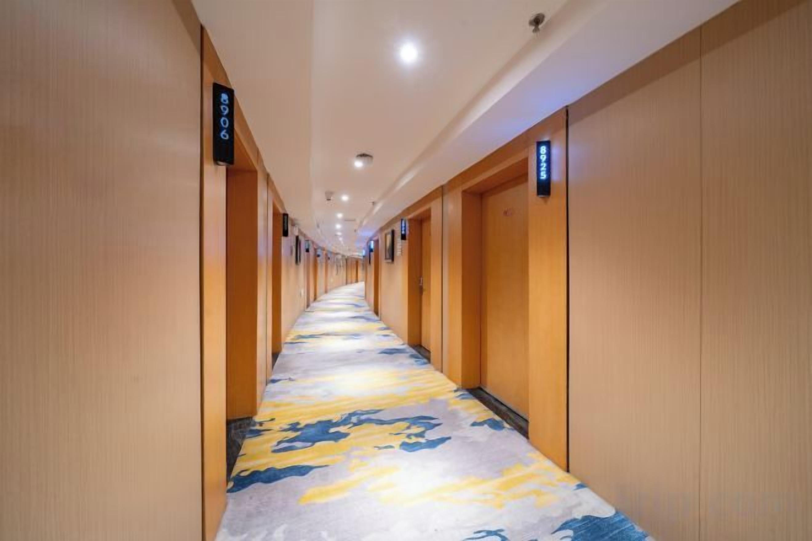 A hotel corridor with wooden walls and a patterned carpet.