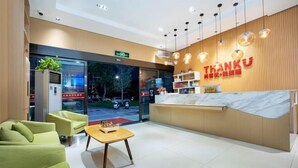 Uma área de recepção de hotel com design moderno, incluindo balcão de atendimento, espaço para sentar e vista para o exterior.