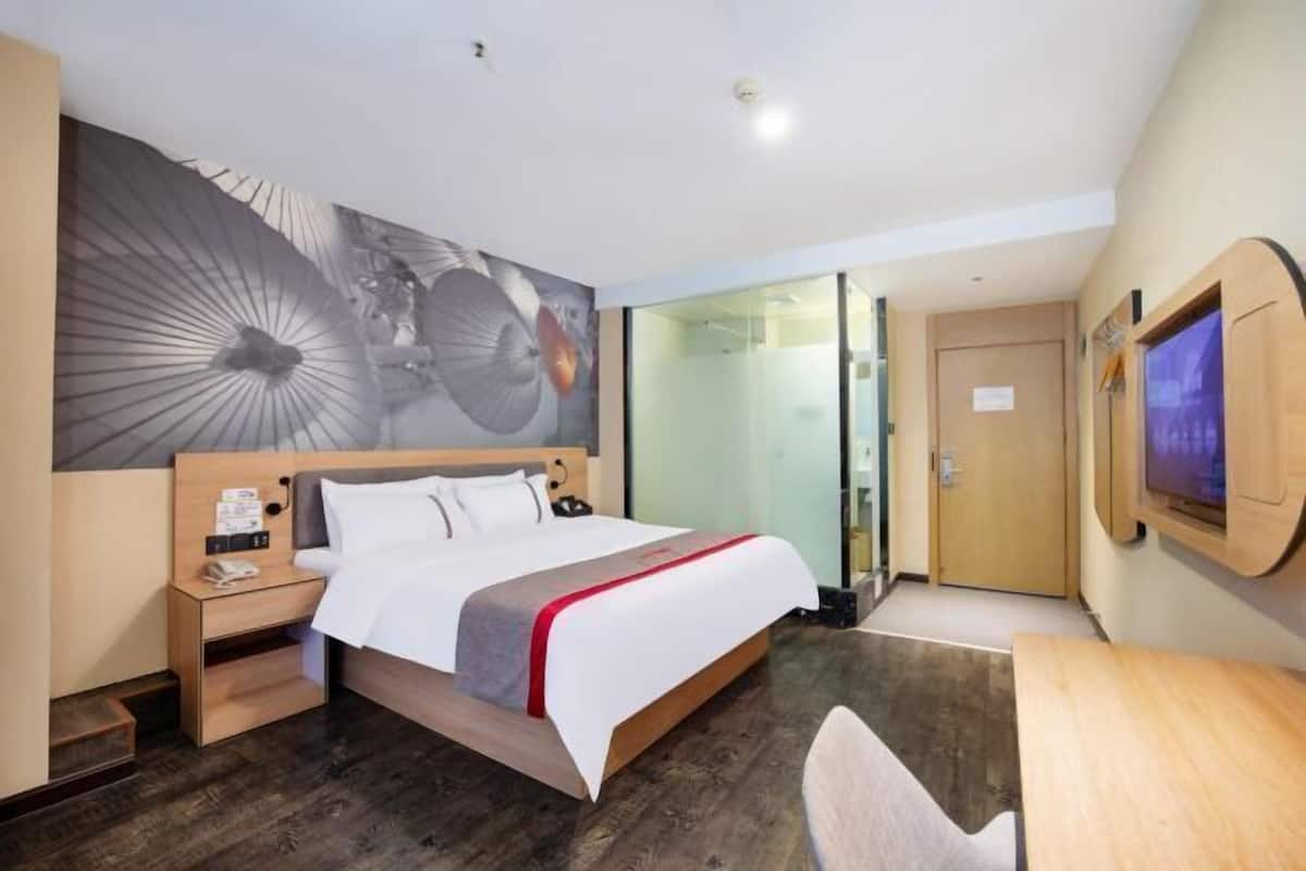 A hotel room with a bed, bedside table, and a large abstract artwork on the wall.