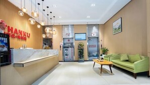 Uma área de recepção moderna com um balcão de madeira, um sofá verde e uma máquina de café.