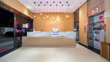 A hotel reception area with a marble counter, a sign reading 'THANKS,' and a vending machine.