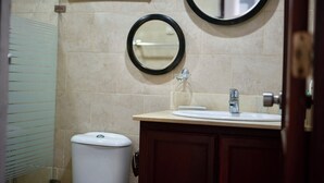 Un baño con inodoro, lavabo y dos espejos en la pared.