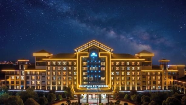 A multi-story hotel with a central atrium, illuminated signage, and a landscaped courtyard. - Days Hotel by Wyndham Suixian Shennong (Sui County)