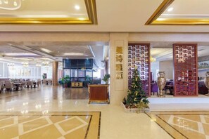 Un hall de hotel con un amplio espacio de asientos, una recepción y una pared decorativa con un árbol de Navidad.