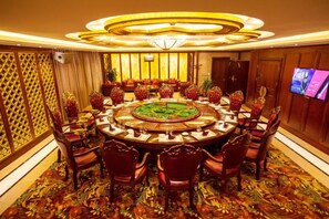 A round table with chairs, a central decorative piece, and a television on the wall. - Days Hotel by Wyndham Suixian Shennong (Sui County)