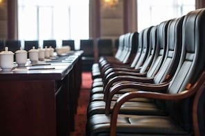 A row of leather chairs with a long table in a room with large windows.