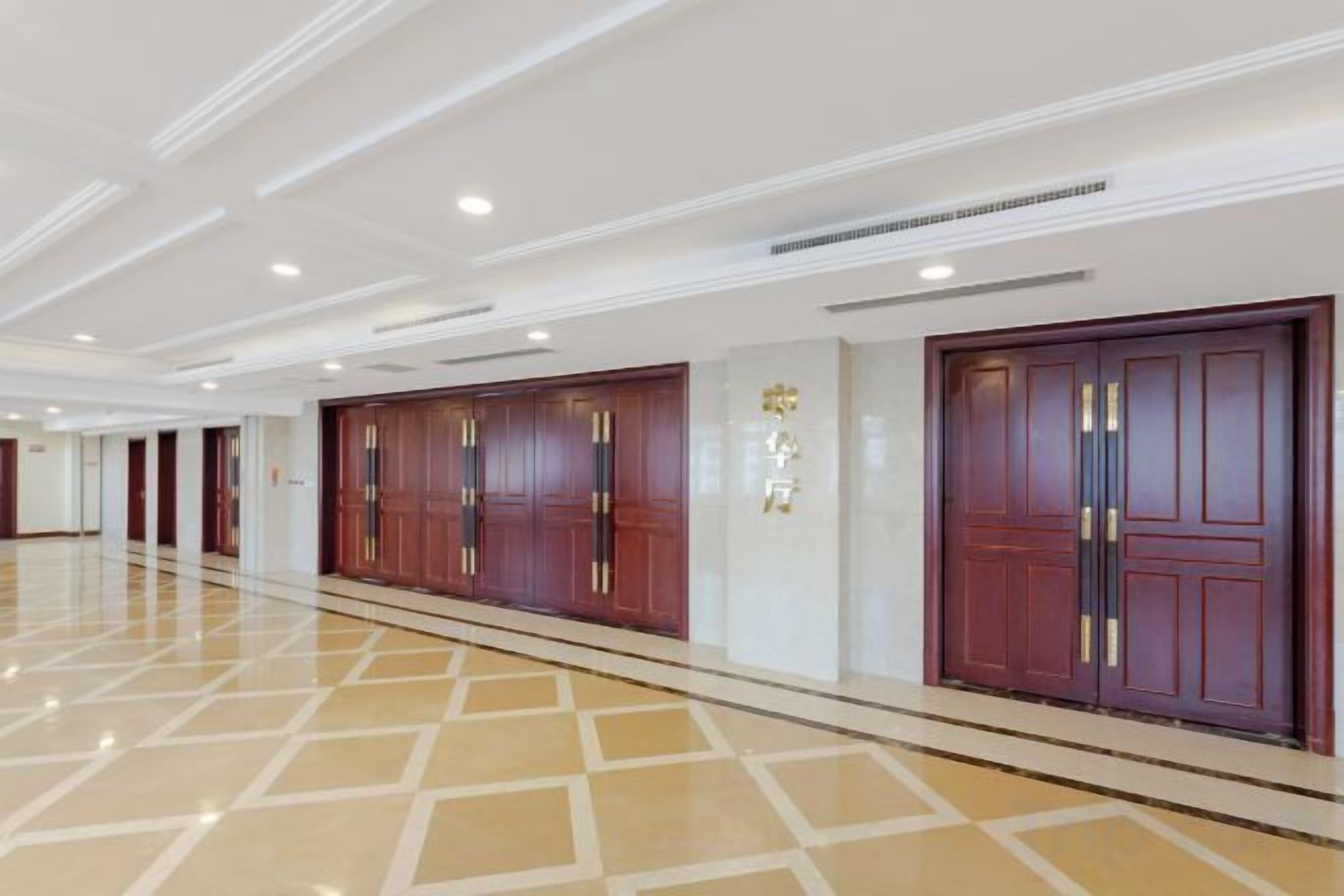 A hotel corridor with multiple doors, a polished floor, and a clean, modern design.