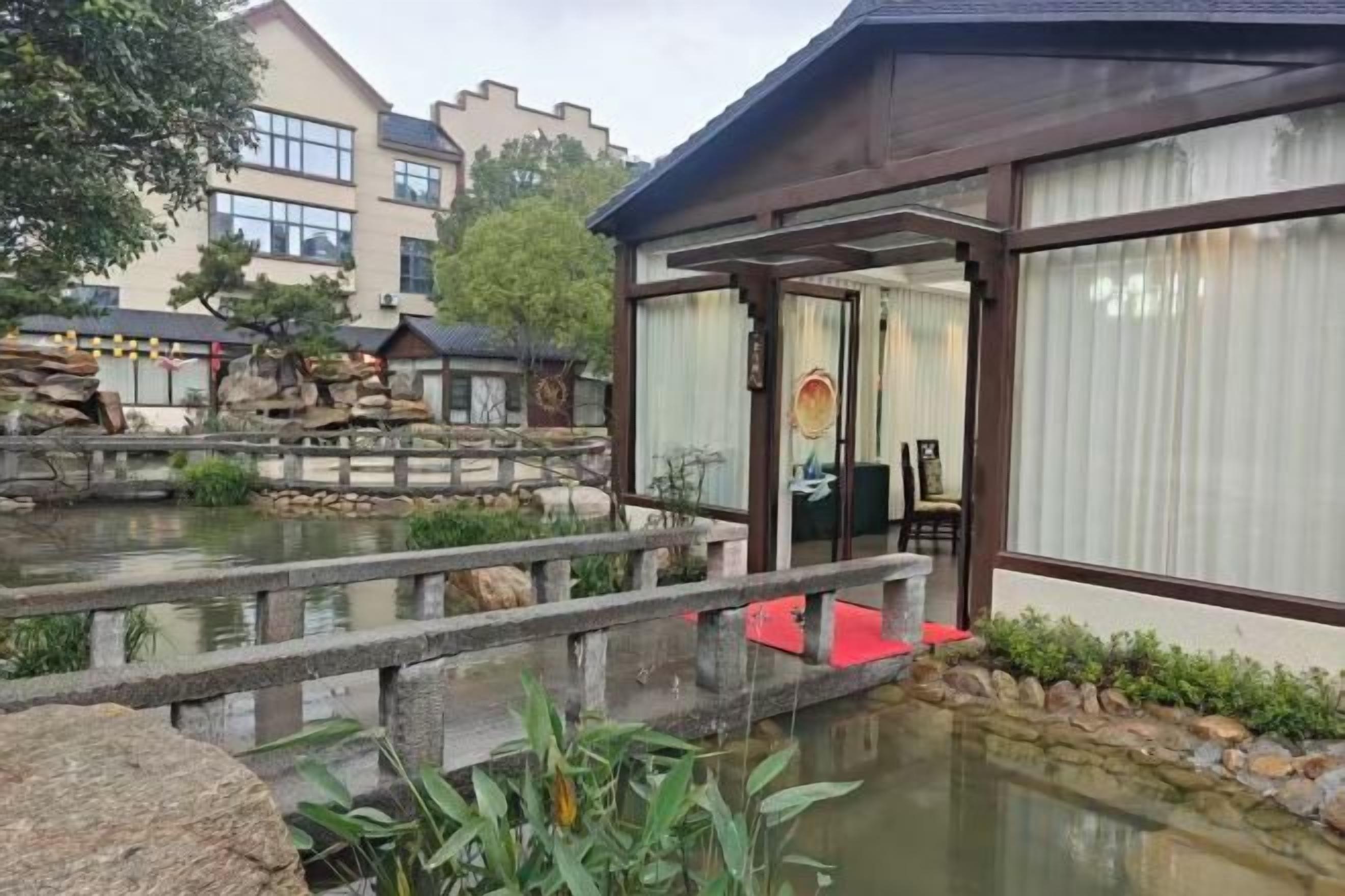 A traditional Japanese-style building with a wooden structure, a koi pond, and a stone bridge.