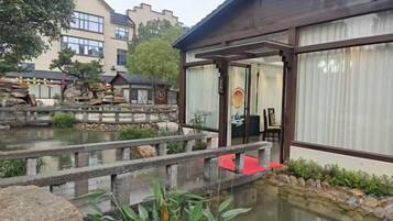 A traditional Japanese-style building with a wooden structure, a koi pond, and a stone bridge.