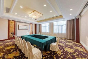 A conference room with a long table, chairs, and a carpeted floor.
