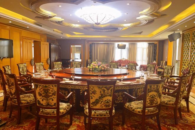 A conference room with a round table, chairs, and a chandelier.
