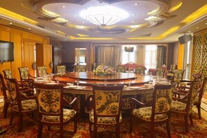 Un salón de conferencias con una mesa redonda, sillas y una araña.