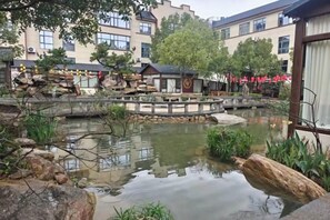 Une cour avec un bassin, un pont de pierre et des bâtiments en arrière-plan.