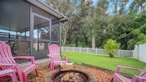 A patio area with a fire pit, red Adirondack chairs, and a glass door leading to a covered outdoor space. - Charming 3-bedroom Pet Friendly house in tranquil Riverview (Riverview)