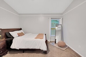 Un dormitorio con cama, cómoda, lámpara y ventana con persianas.