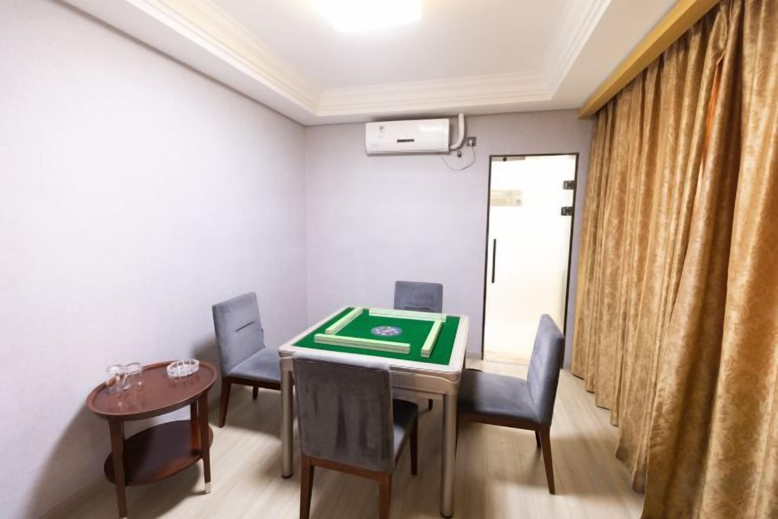 Une pièce avec une table de billard, deux chaises, une petite table avec des verres et une porte.