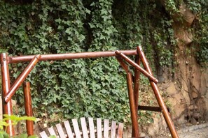 A wooden swing set against a backdrop of dense foliage and a rocky wall. - Kunshan Lushan Resort (Kunshan)