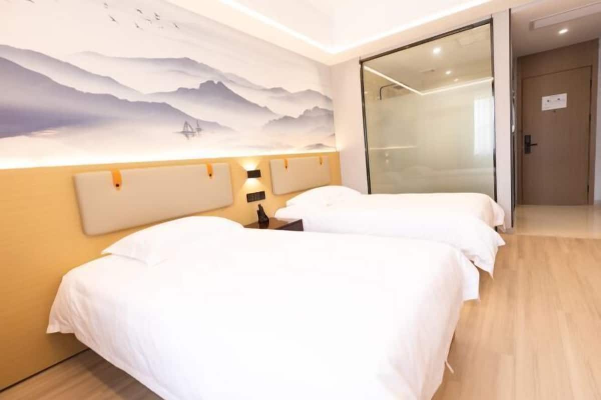 Une chambre d’hôtel avec deux lits, une fresque murale et une porte coulissante.