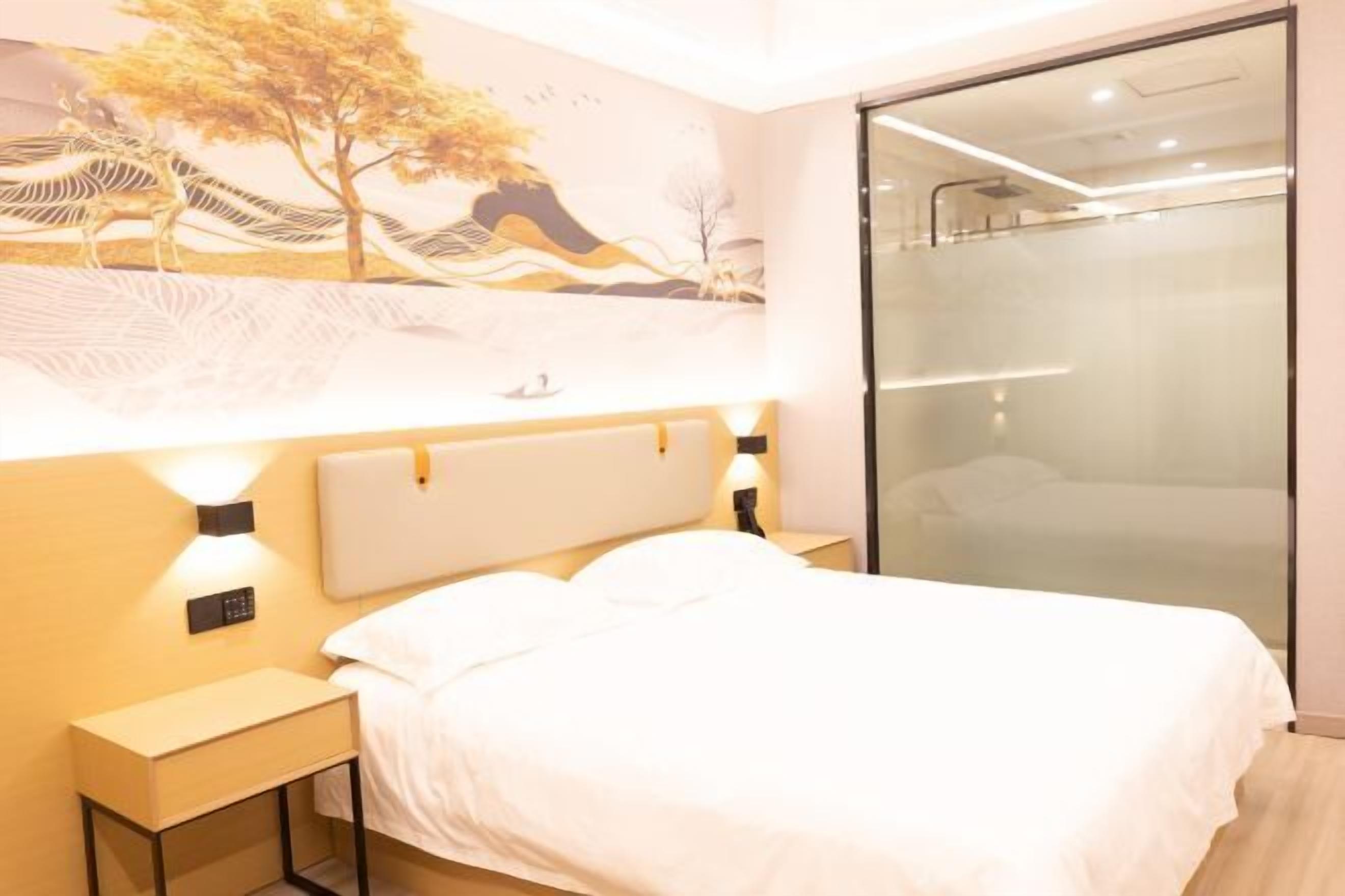 Ein modernes Hotelzimmer mit einem großen Bett, einem Nachttisch, einer wandmontierten Steuerung und einer Duschkabine aus Glas.