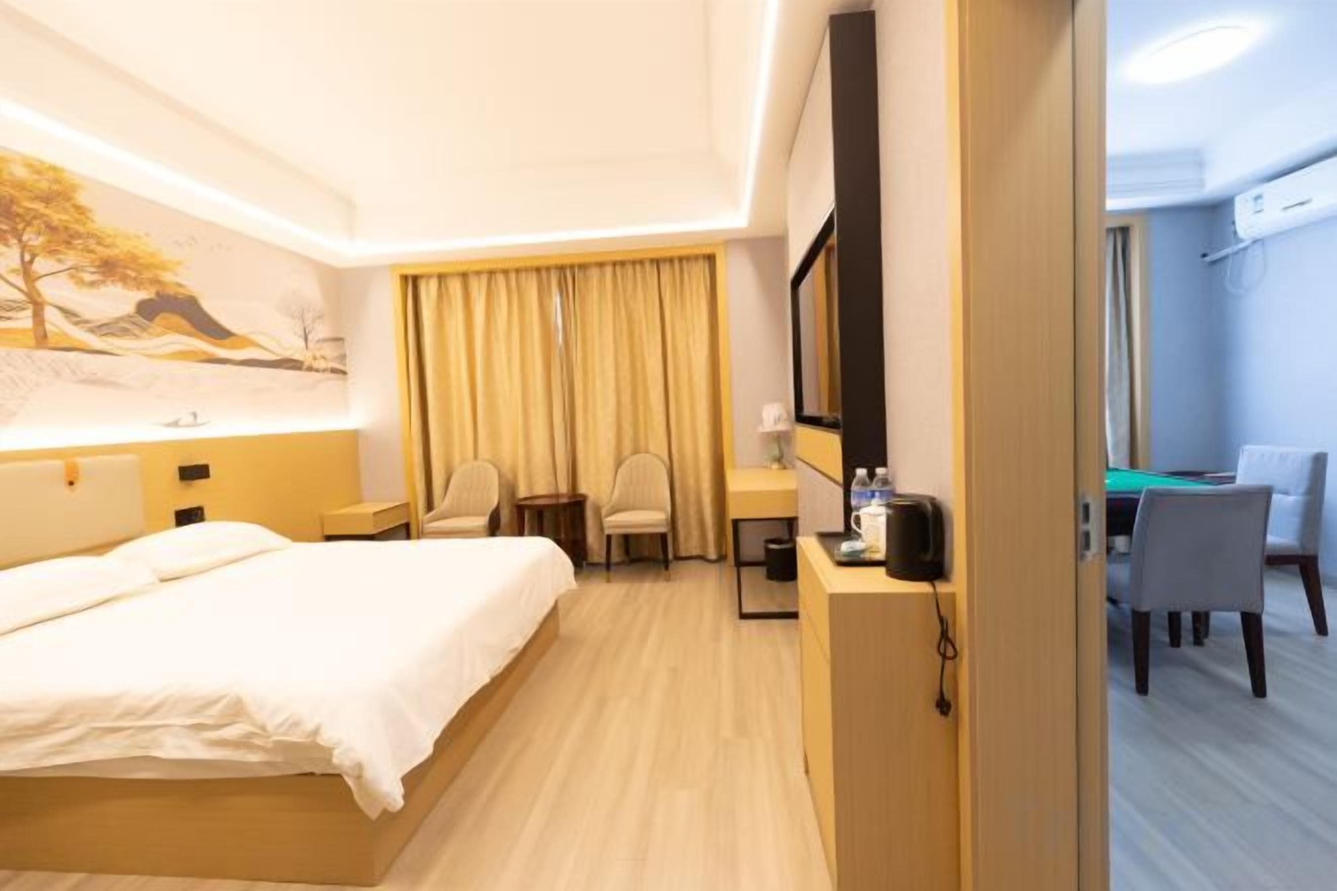 A hotel room with a bed, a desk, a chair, and a dining area.
